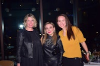 three women posing for a photo at an event