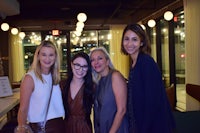 four women posing for a photo at an event