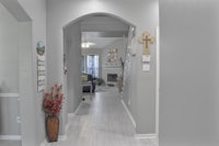 a hallway in a home with white walls and wooden floors